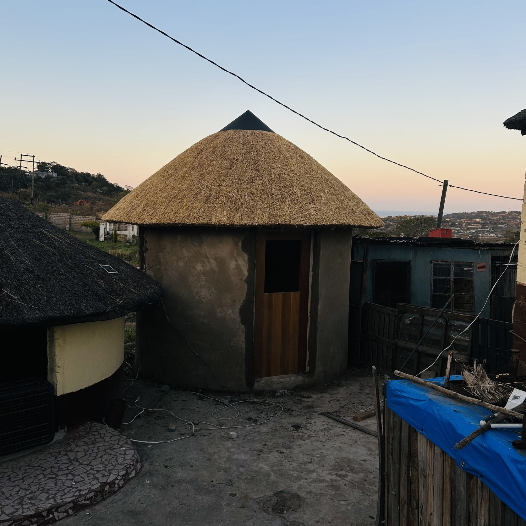 Traditional thatch rondavel with conical roof at dusk